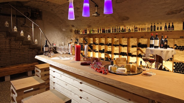 Un bar con mostradores de madera, botellas de vino y una vela.