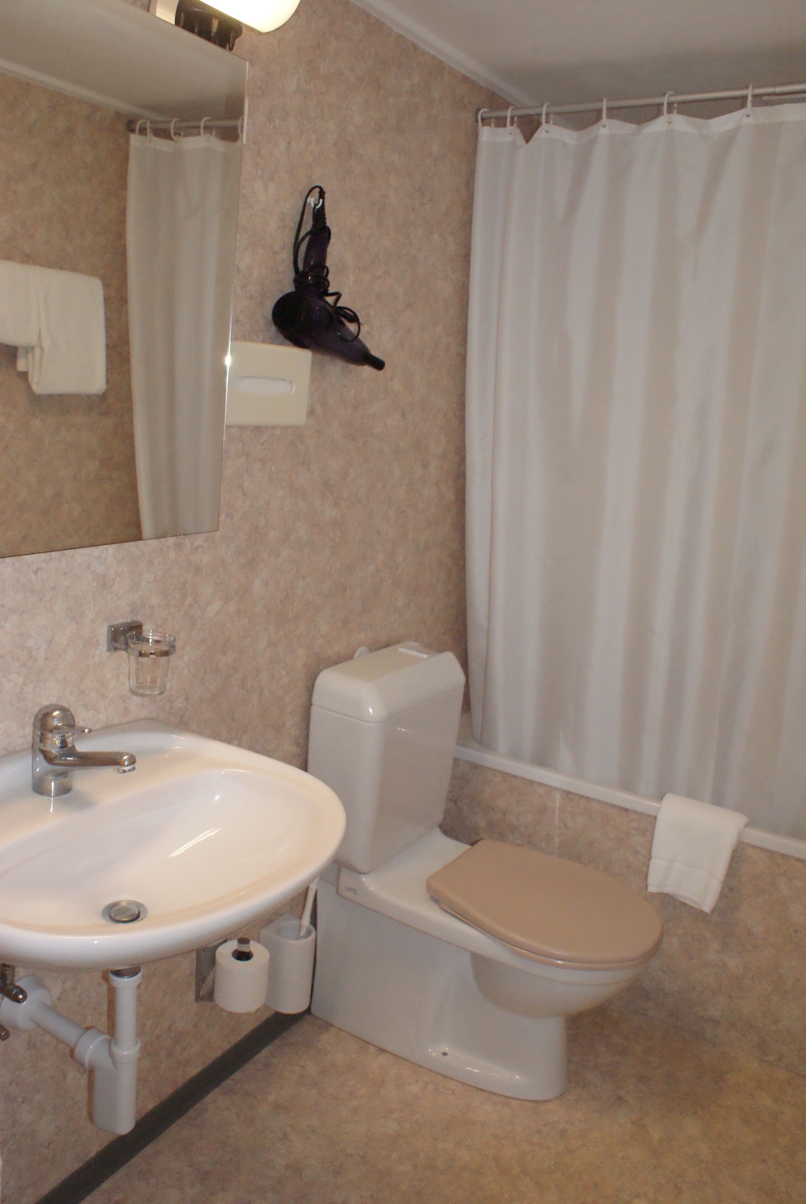 Un baño con lavamanos, inodoro y cortina de ducha.