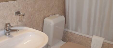 Un baño con lavamanos, inodoro y cortina de ducha.