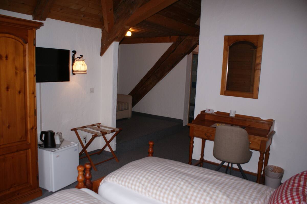 Una habitació petita i acollidora amb un llit, un escriptori, una cadira, una televisió i un armari de fusta.