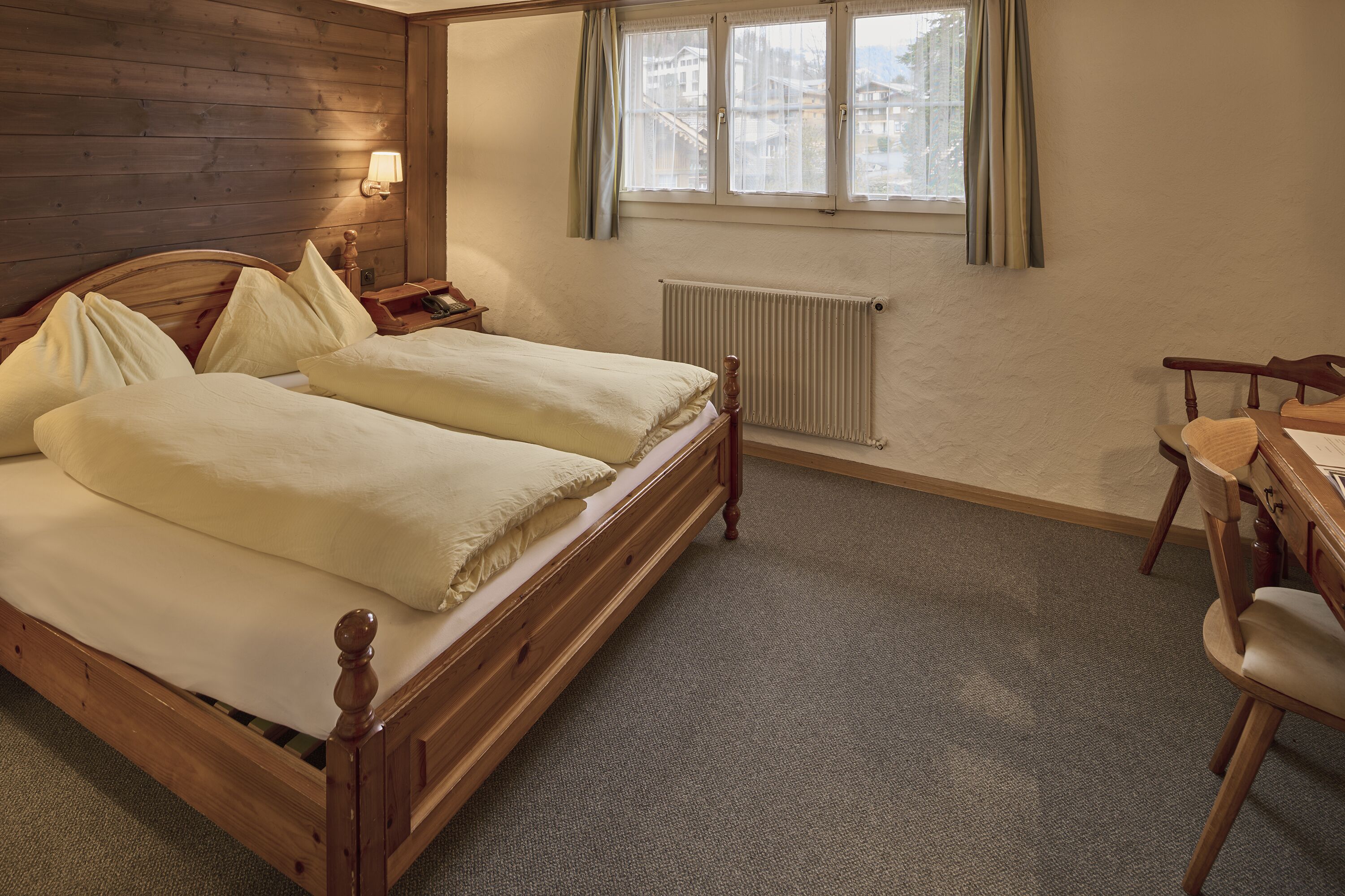 Una habitación de hotel con una cama de madera, un escritorio y una silla.
