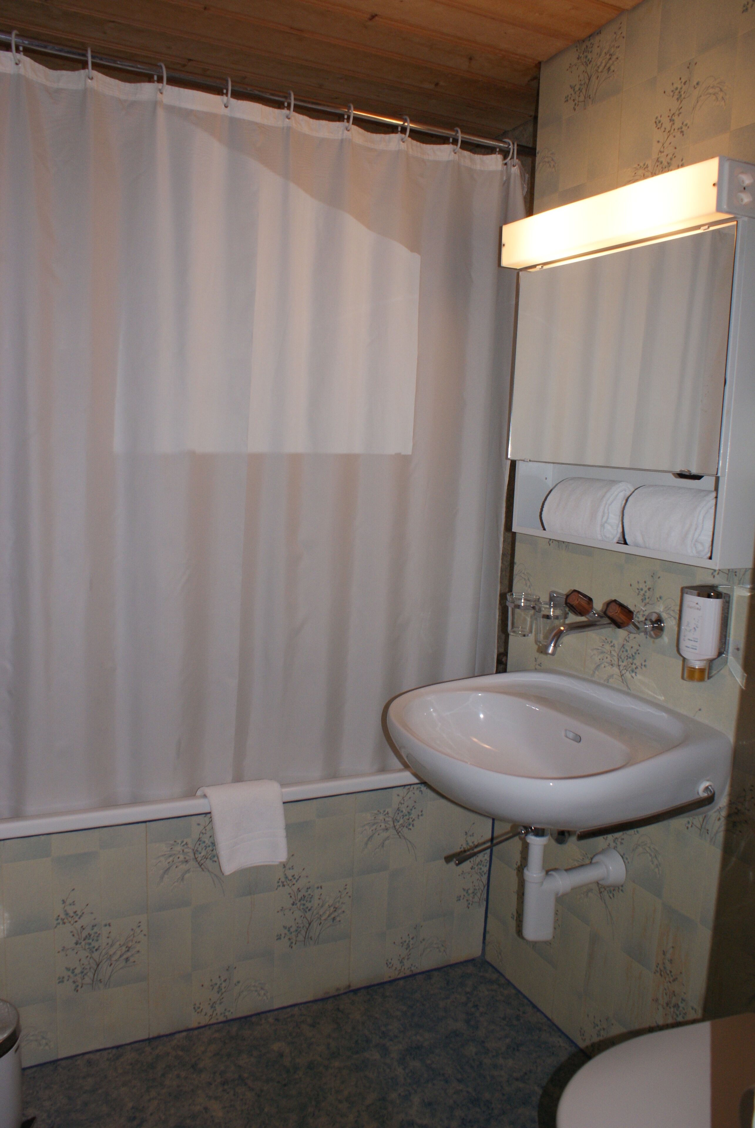 A bathroom with a shower curtain, a sink, a mirror, and a towel rack.