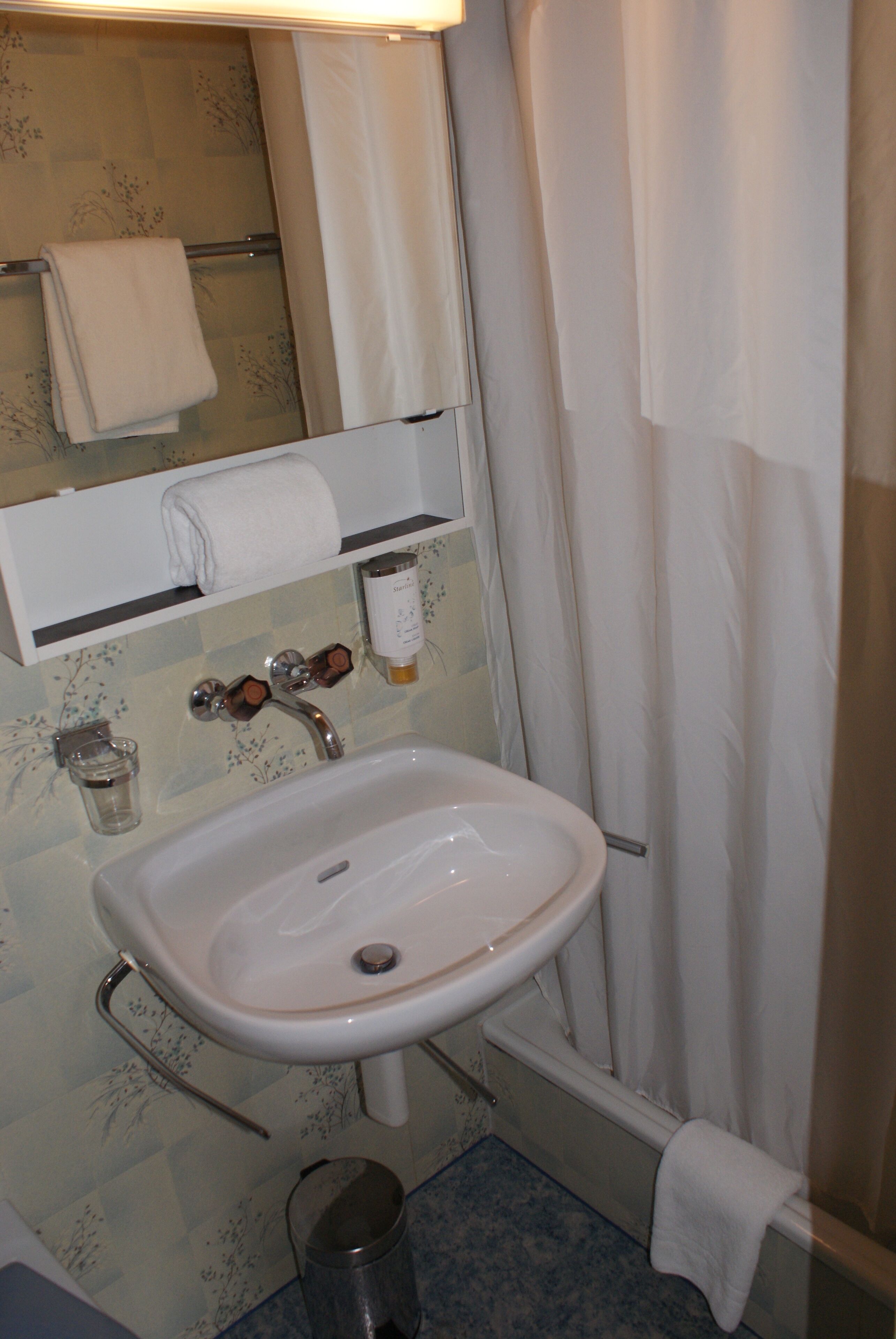 Un baño con lavamanos, espejo y cortina de ducha.