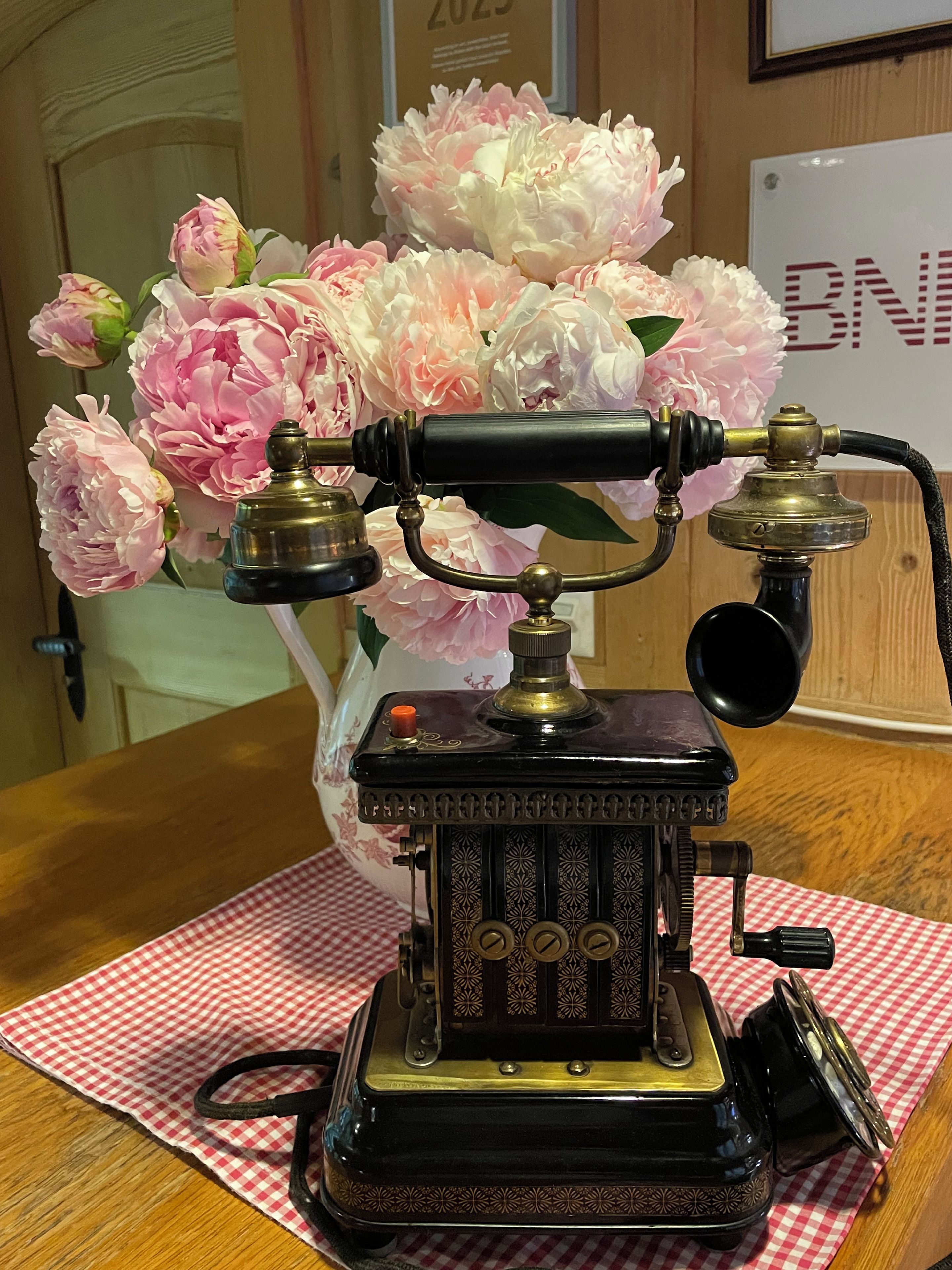 A vintage typewriter with a brass finish, placed on a checkered tablecloth.