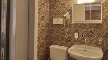 A bathroom with a mosaic tile wall, a toilet, a sink, and a mirror above the sink.