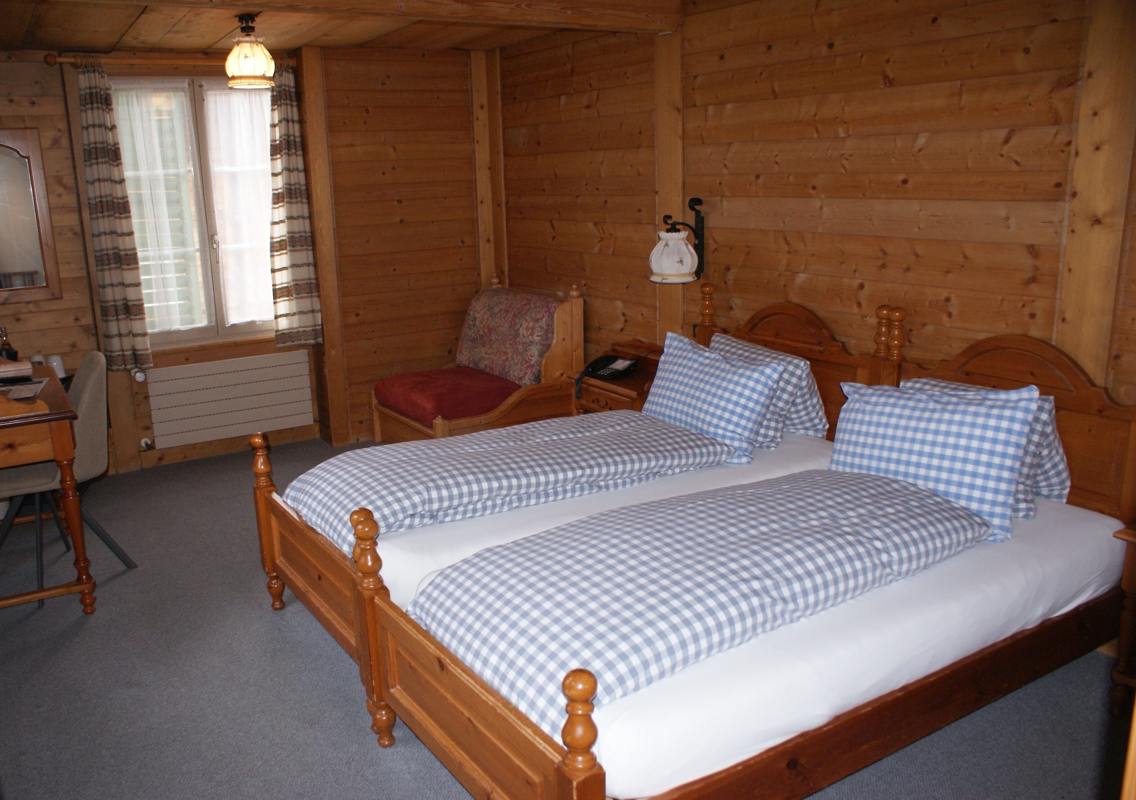 Une chambre dans une cabane en bois, avec un lit double, une chaise, une table de chevet et une lampe.