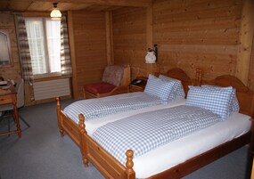 Un dormitorio de cabaña de madera con una cama doble, una silla, una mesita de noche y una lámpara.