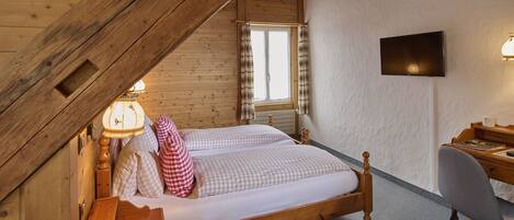 Een slaapkamer met een houten plafond, een bed, een bureau en een televisie.