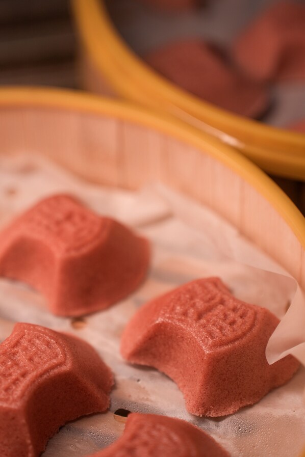 A close-up of a yellow baking dish with several pink, textured items inside, possibly food items. - Zhejiang Narada Grand Hotel (Hangzhou)