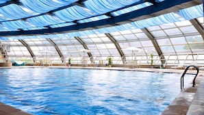 An indoor swimming pool with a glass ceiling and multiple lounge chairs. - Zhejiang Narada Grand Hotel (Hangzhou)