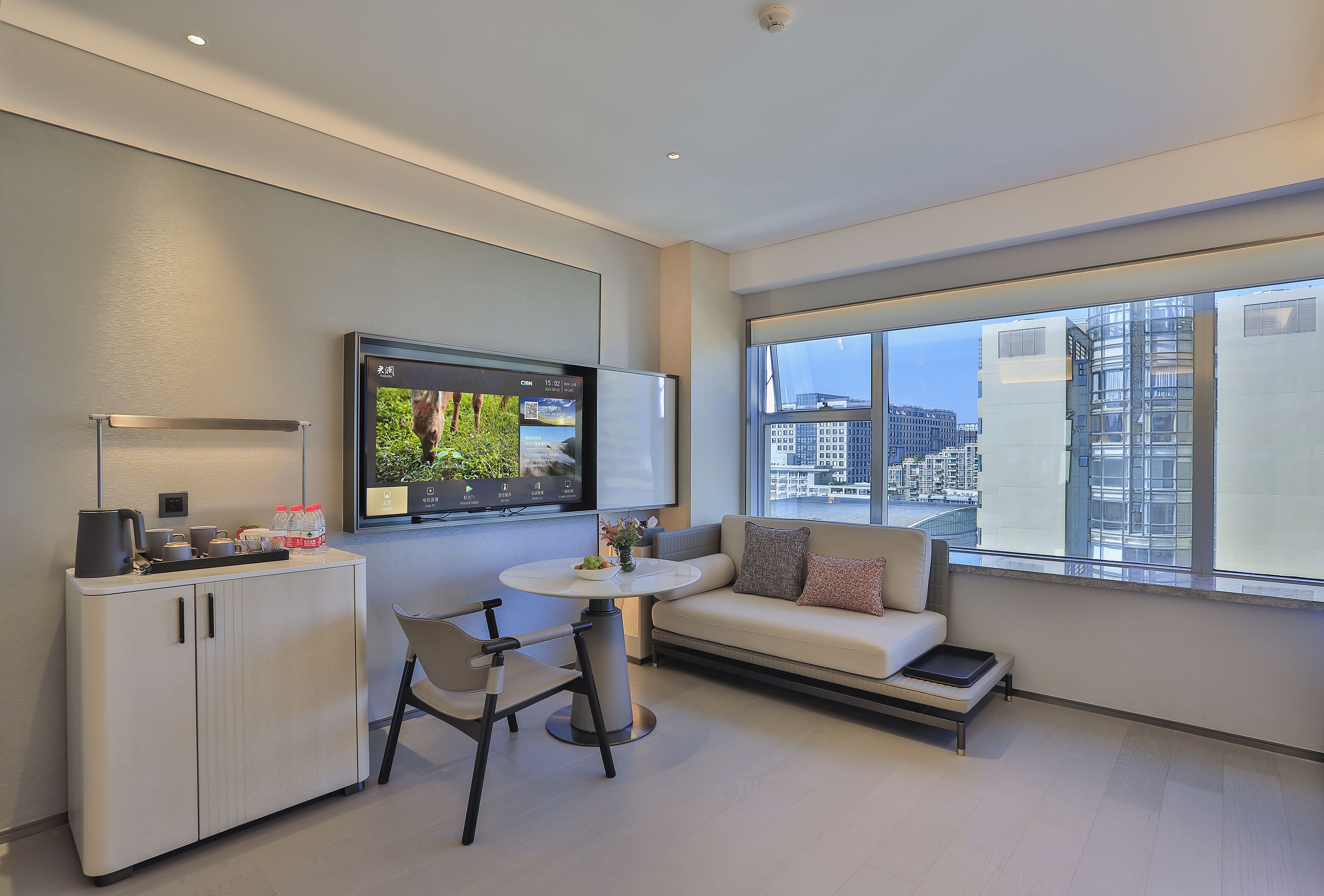Una sala de estar moderna con un sofá, una mesa de comedor y un televisor montado en la pared.