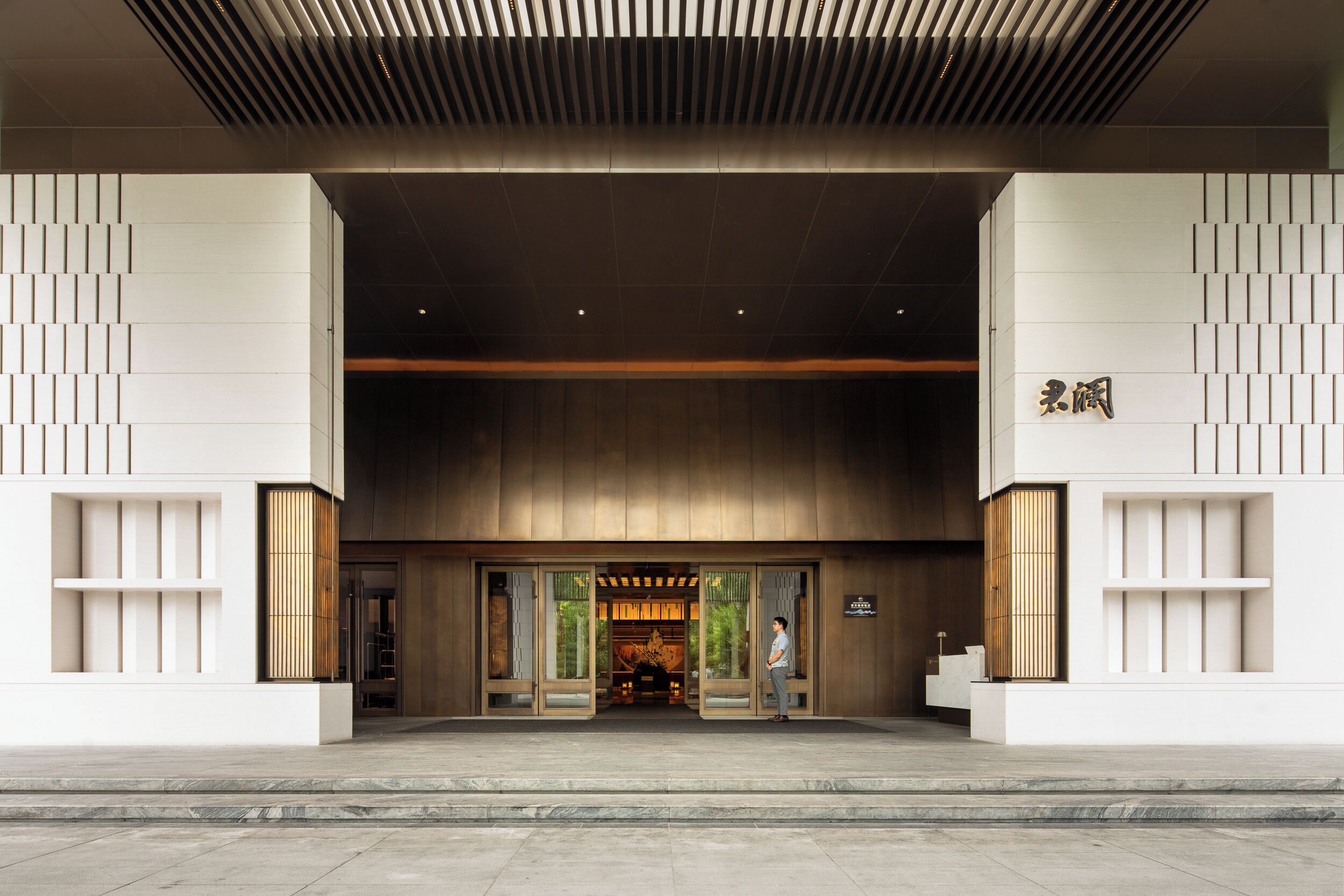 A modern building entrance with a large overhang and a sign with Chinese characters.