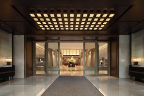 A hotel lobby with a glass door entrance, a central reception desk, and a carpeted floor. - Narada Grand Hotel Hangzhou Westlake (Hangzhou)