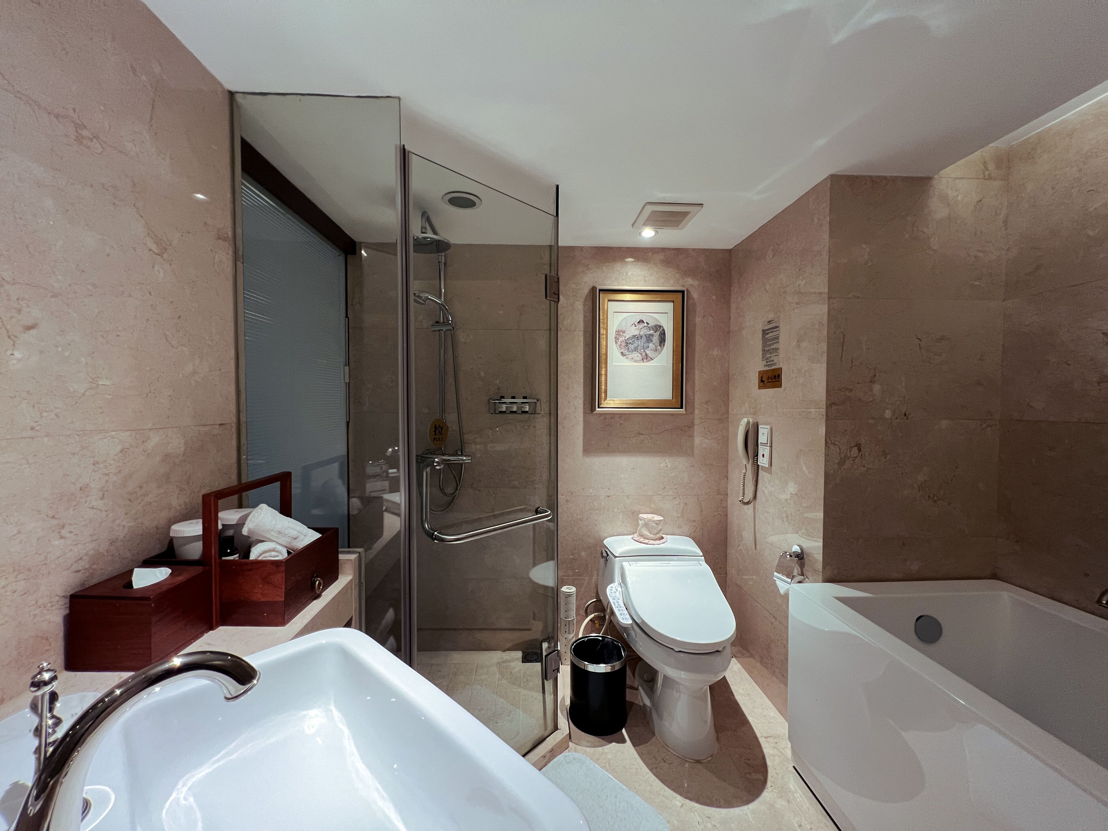 A modern bathroom with a glass-enclosed shower, a bathtub, a toilet, and a bidet.