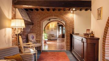 Una sala de estar acogedora con chimenea, un sofá a rayas, un mueble de madera y un arco de ladrillo que da a otra habitación.