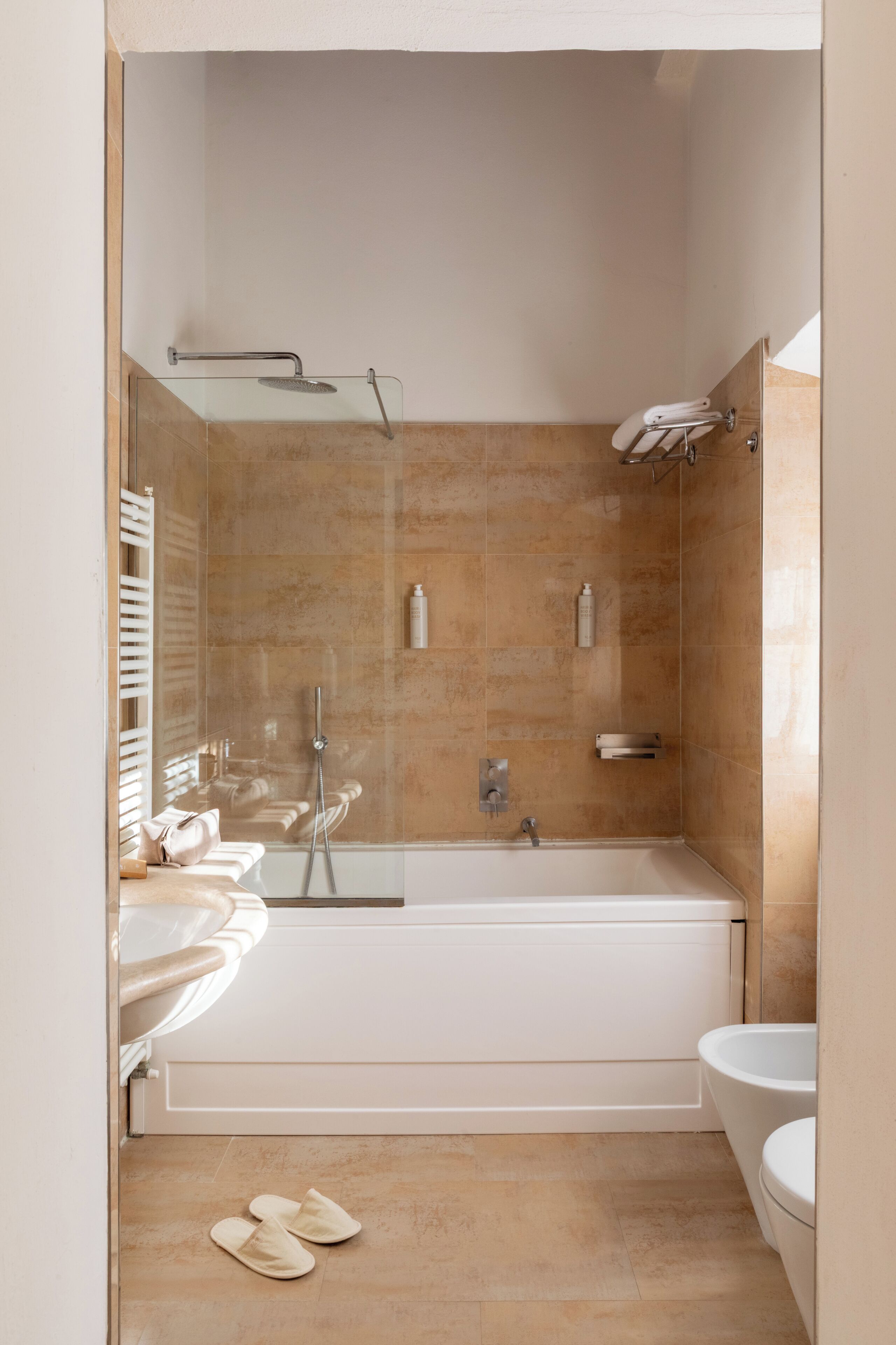 A modern bathroom with a glass-enclosed shower, a standalone bathtub, and a toilet.