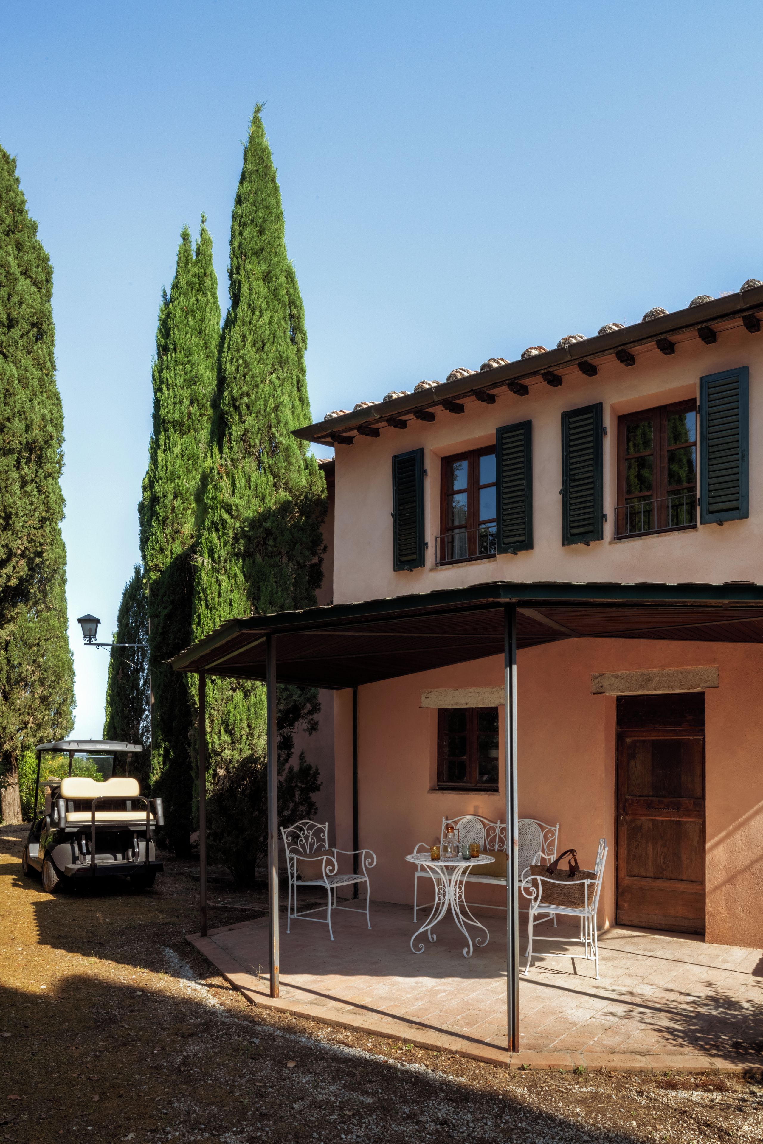 A villa with a covered patio, outdoor seating, and a vehicle parked nearby.