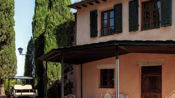 A villa with a covered patio, outdoor seating, and a vehicle parked nearby.