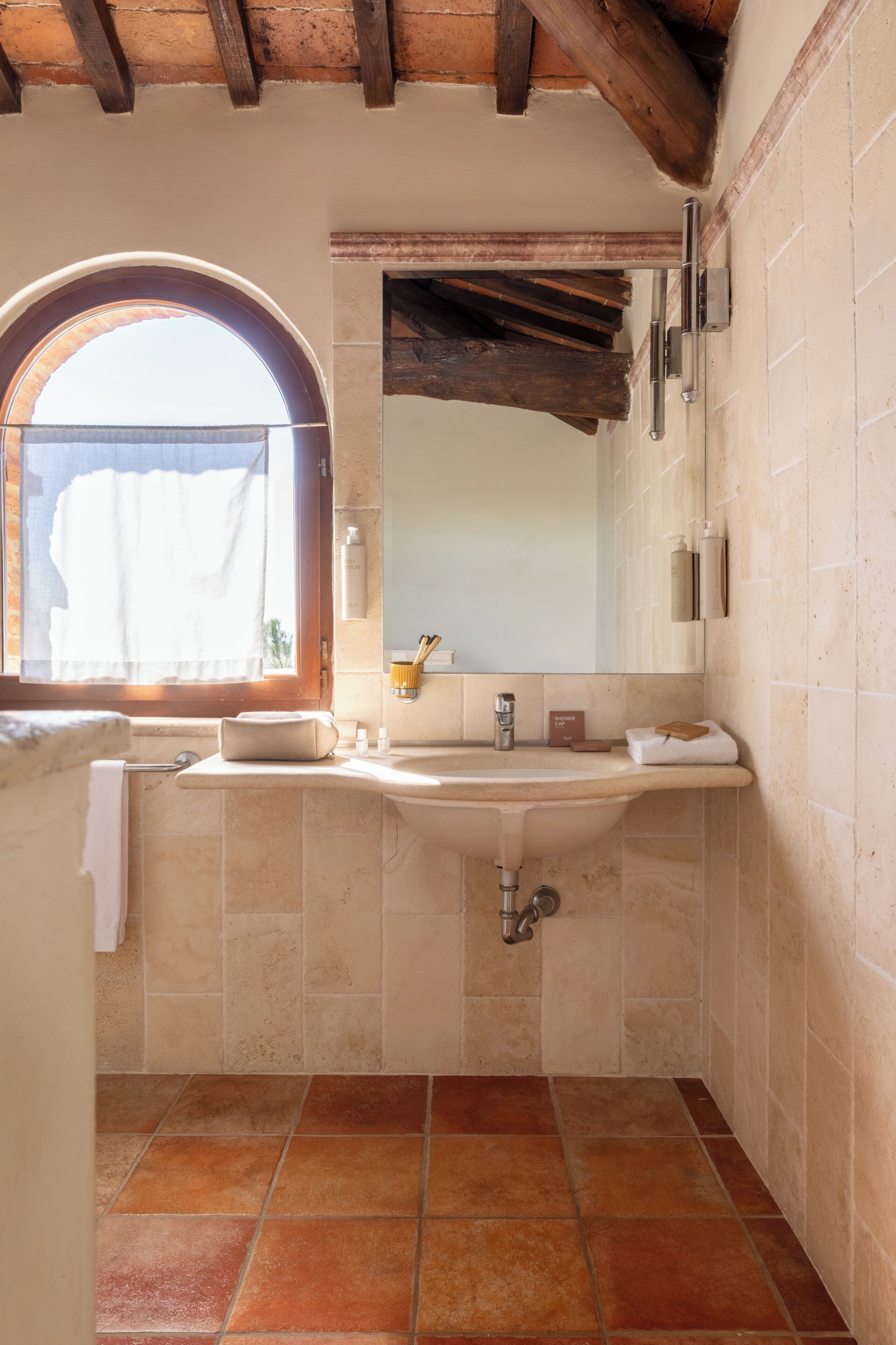 Une salle de bain avec un lavabo, un miroir et une fenêtre.