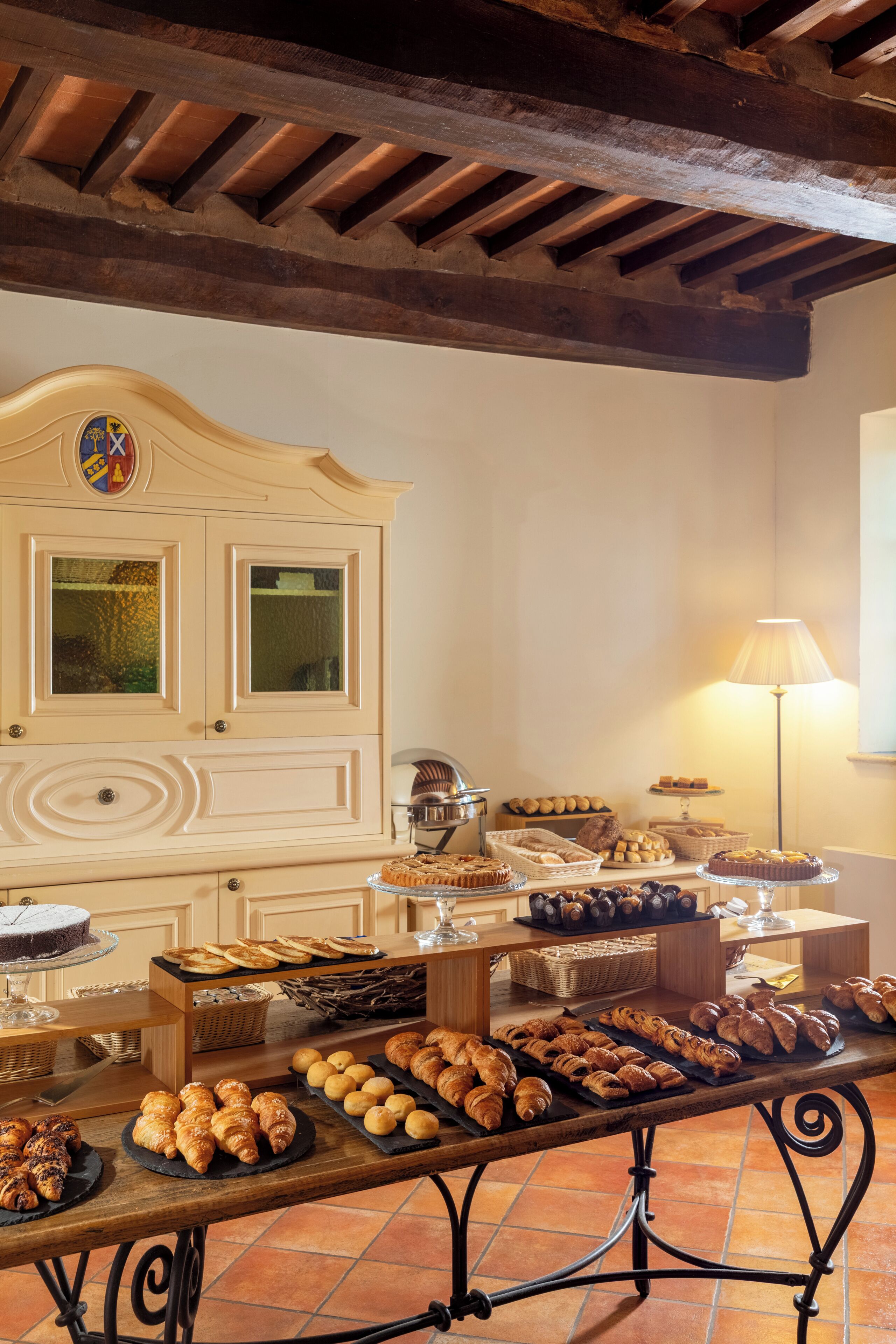 Ein Buffet mit verschiedenen Backwaren und Gebäck, eine dekorative Vitrine und eine Lampe.