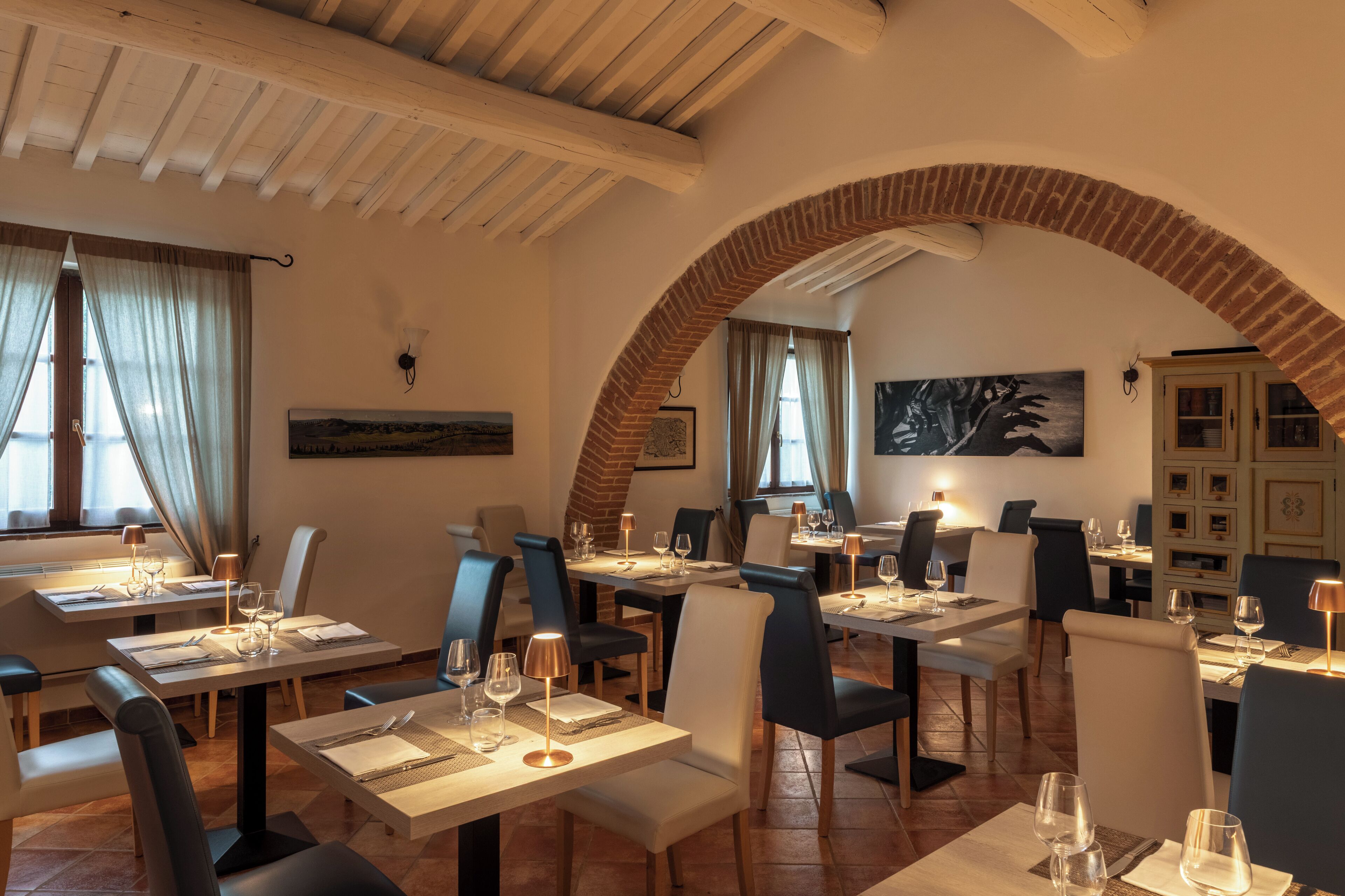 Ein Restaurant mit gedeckten Tischen, einem Ziegelbogen und Kunstwerken an den Wänden.