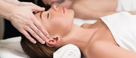 A person receiving a head massage with a towel and a rolled towel on the side.