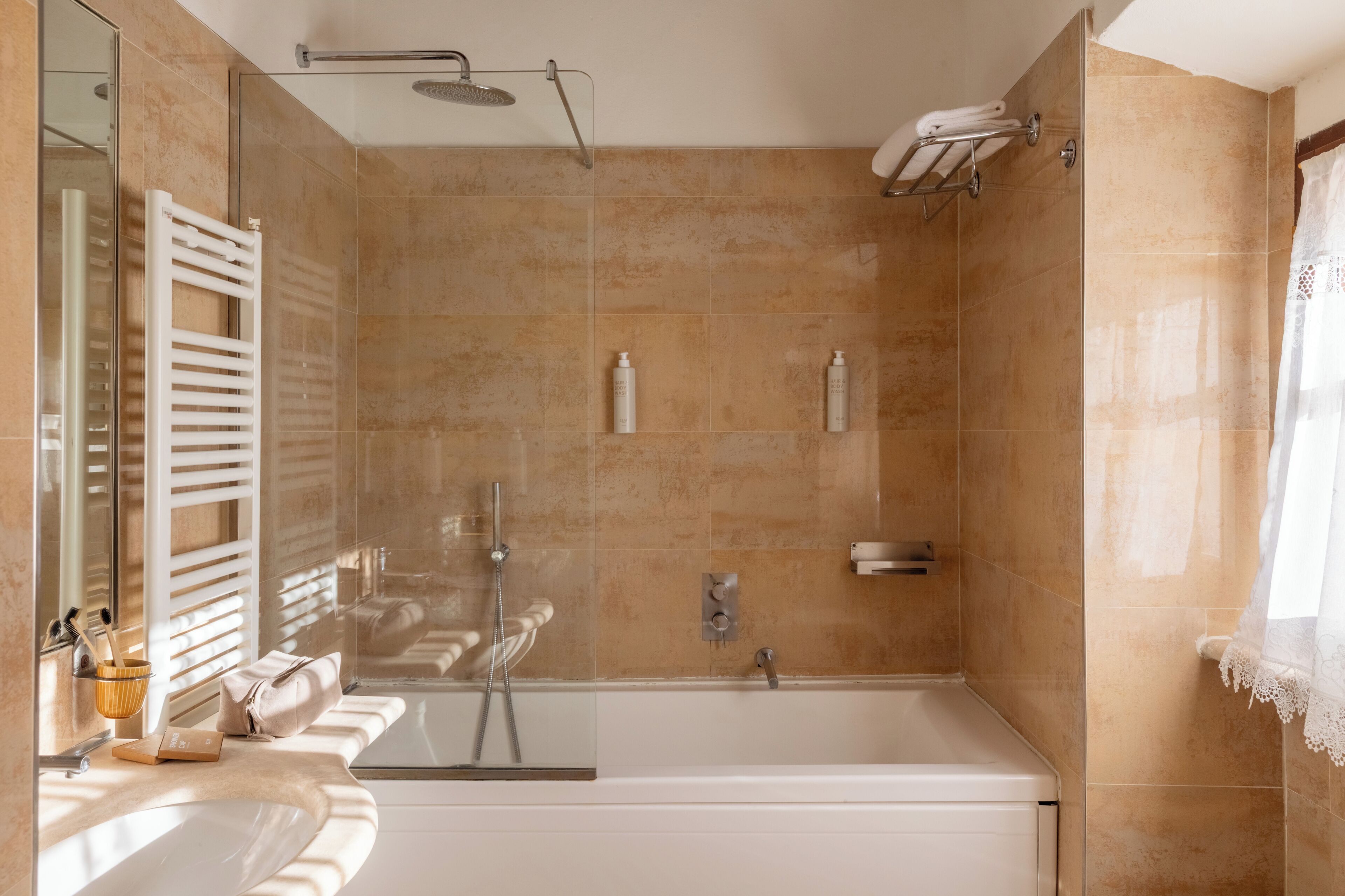 Un baño moderno con bañera, ducha y un espejo grande.