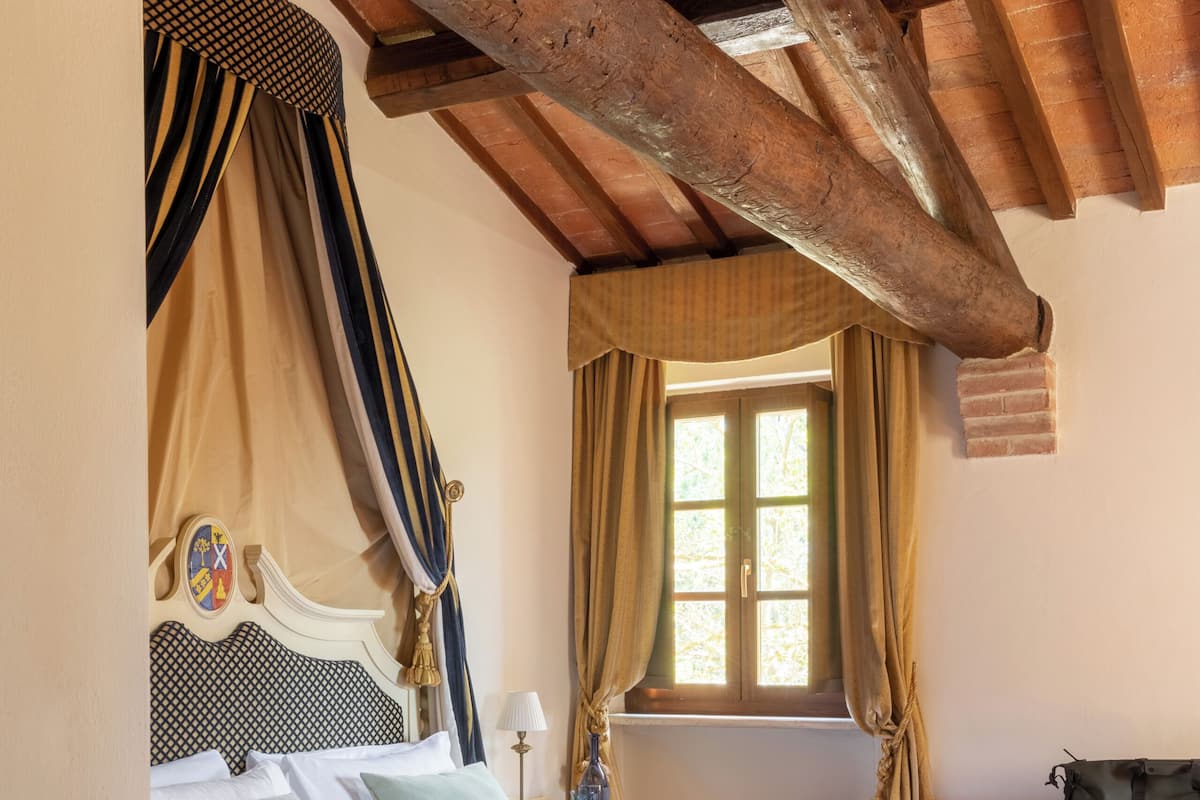 Un dormitorio con cama, cortinas, una ventana y techo de madera.