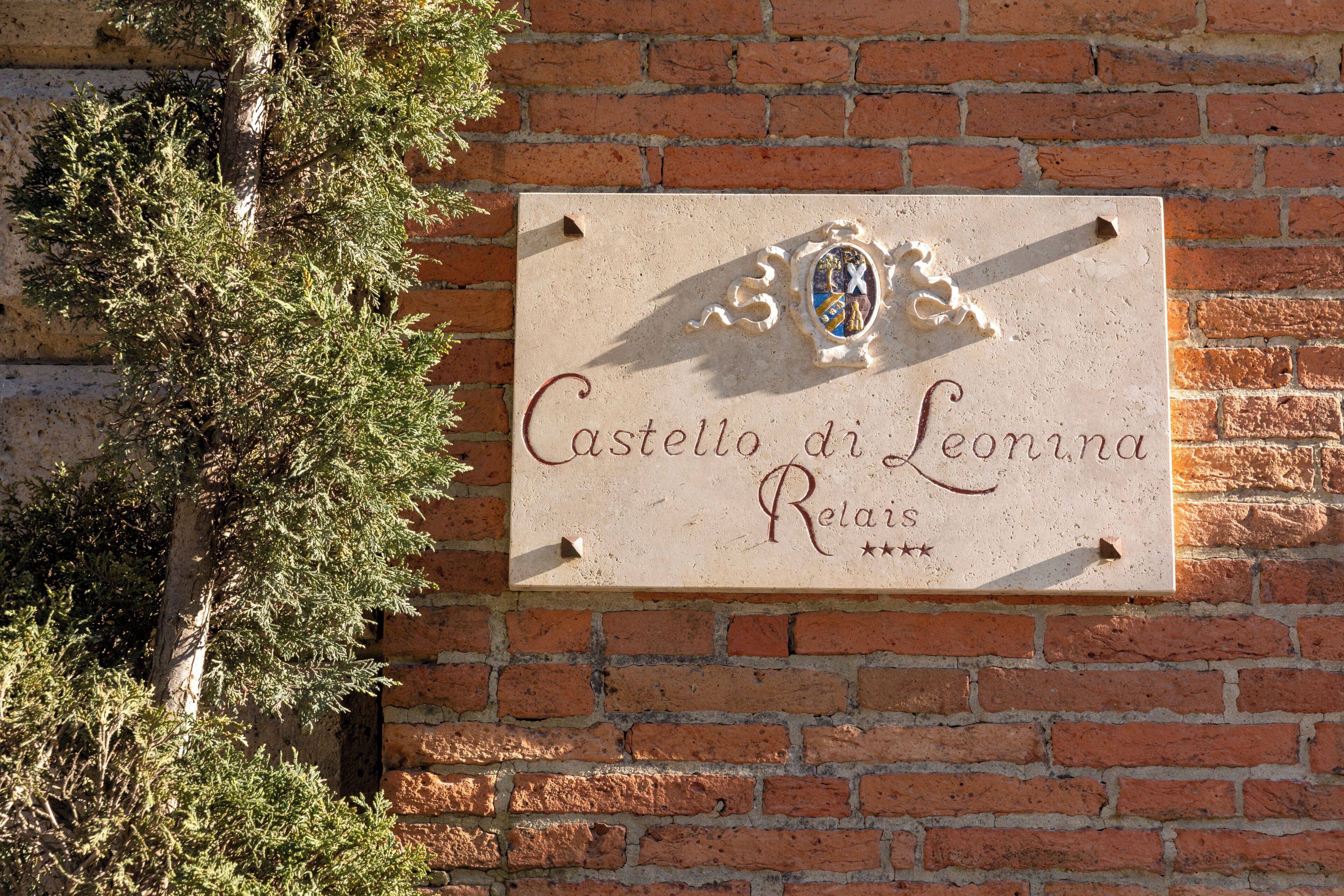 A sign with the text 'Castello di Leonina Reti' on a brick wall.