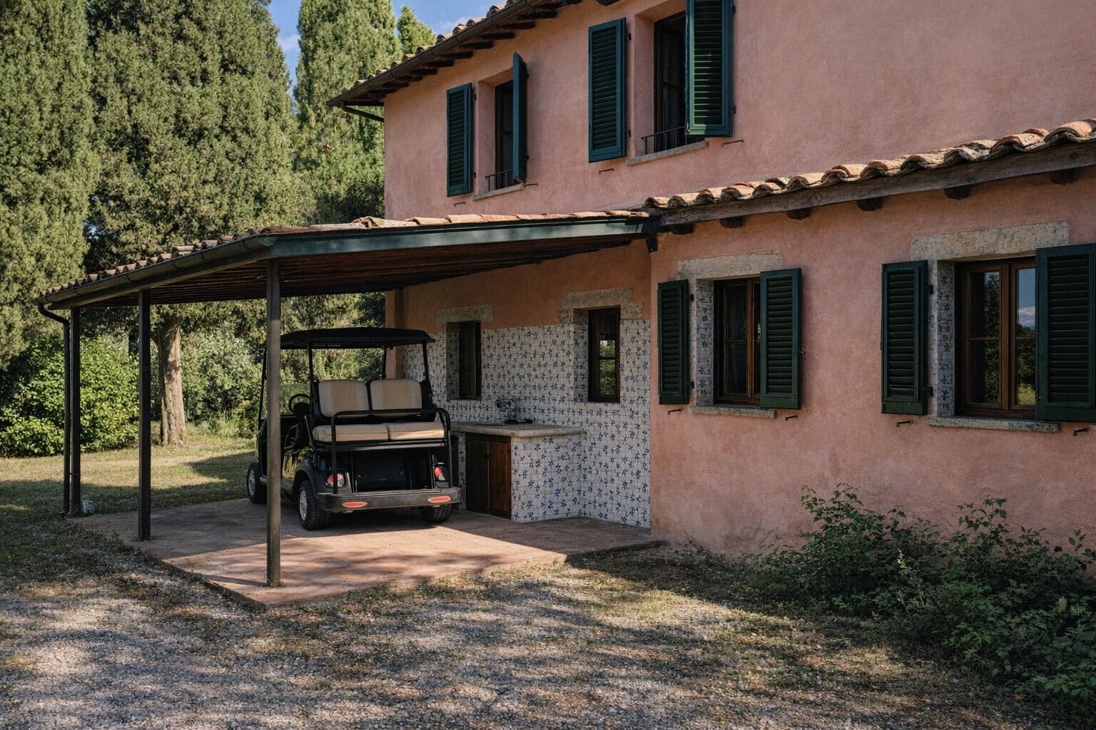 Ein Haus mit überdachter Terrasse, einem Golfwagen und einer gefliesten Küchenzeile.