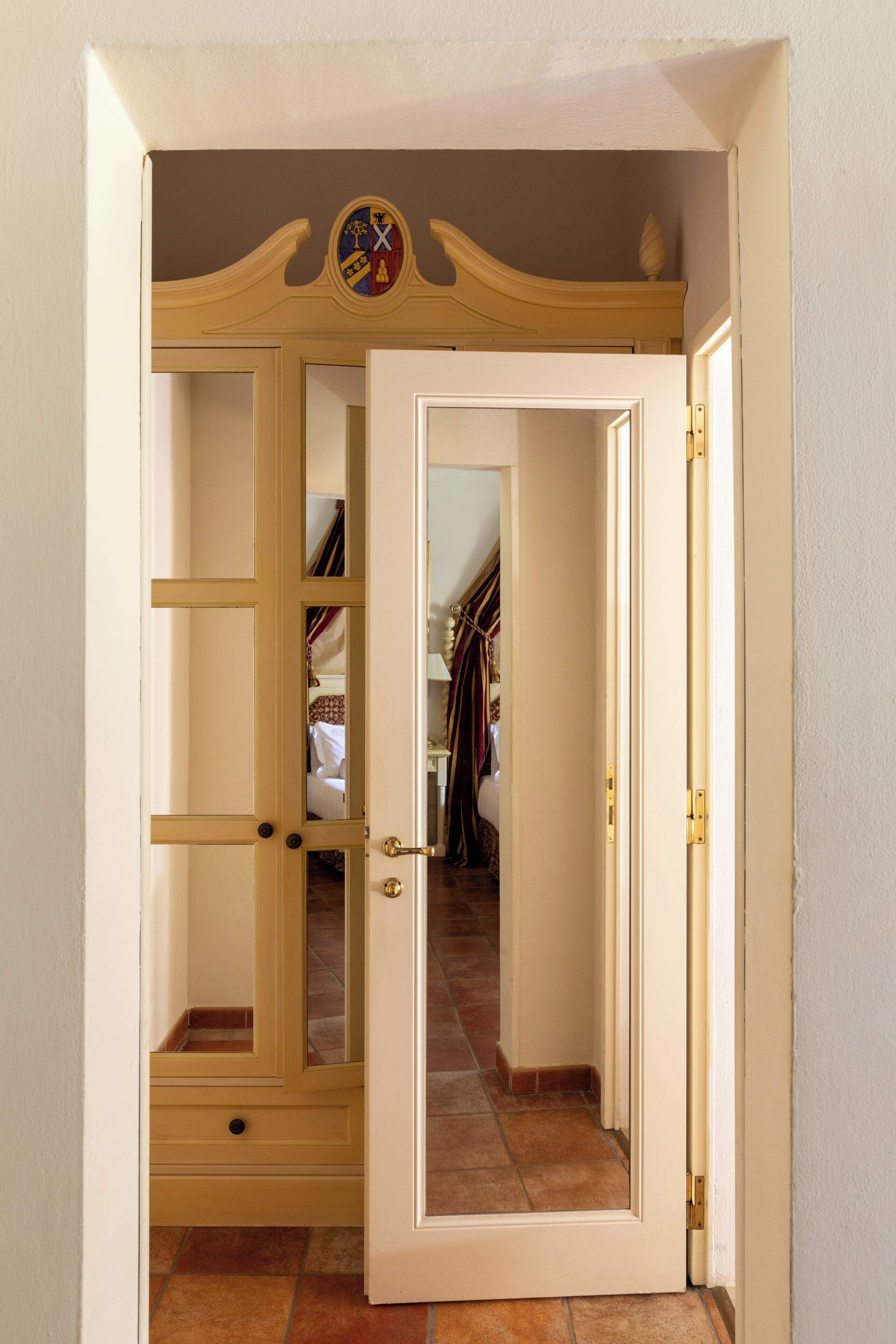 Ein Zimmer mit einem großen Spiegel, einem Kleiderschrank und einer Tür zu einem weiteren Raum.