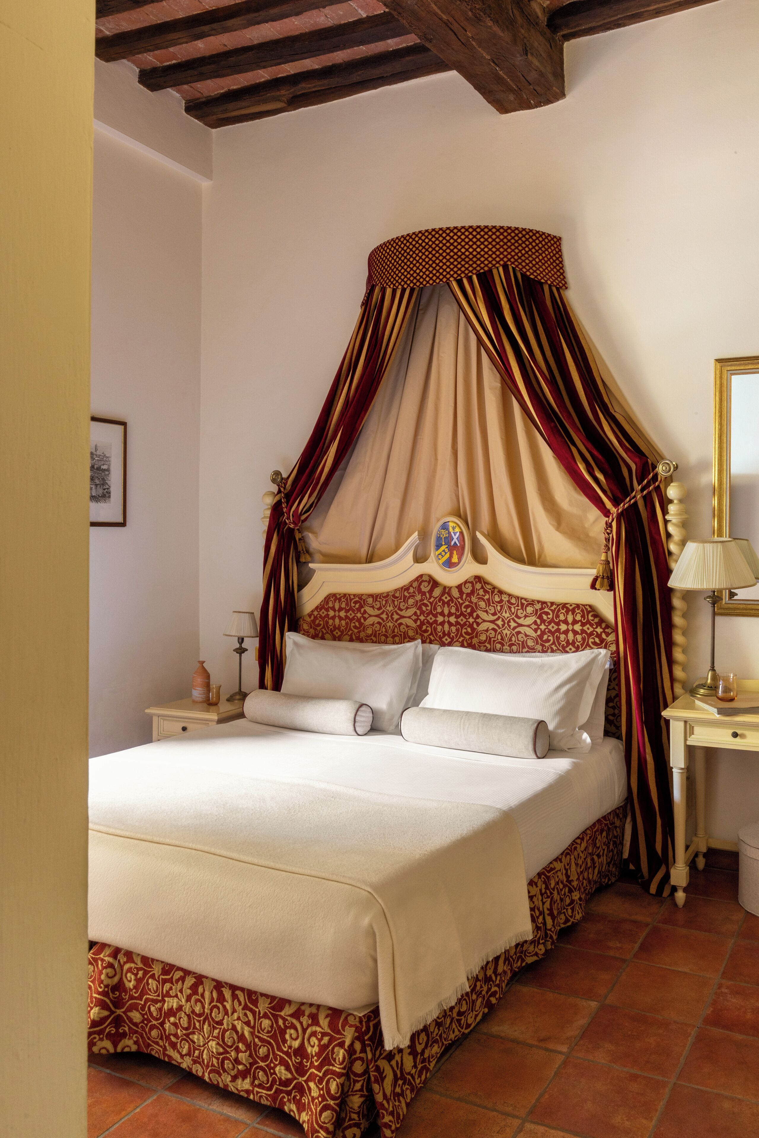 Een slaapkamer met een hemelbed, nachtkastje en een spiegel.