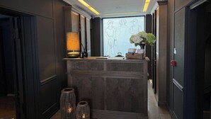 A reception desk with a lamp, a vase with flowers, and a wall-mounted screen displaying a drawing. - Hotel Maritime (Copenhagen)