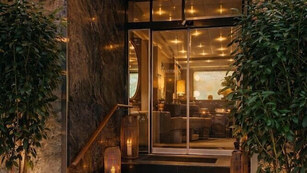 A hotel entrance with a stone facade, glass doors, and steps leading to a lobby. - Hotel Maritime (Copenhagen)