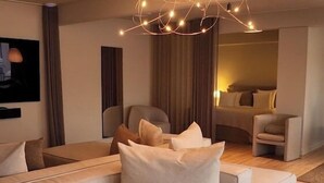 A modern living room with a large sectional sofa, a small round table, and a unique light fixture. - Hotel Maritime (Copenhagen)