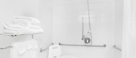 Une salle de bain blanche avec une douche, des toilettes et une barre d’appui.