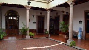 Un patio con suelo de baldosas, plantas en macetas y puertas de madera.