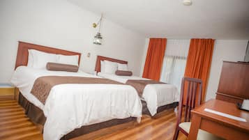 A hotel room with two beds, wooden flooring, a desk, and a chair.