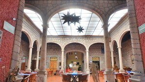 Un lobby espacioso con altos arcos de piedra, un área central abierta con mesas y una decoración de estrellas en el techo.