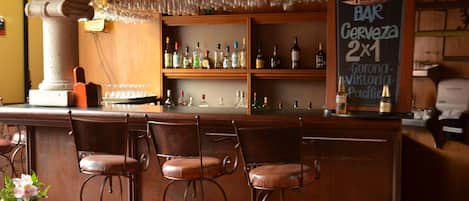 A bar area with a chalkboard menu, bar stools, and shelves stocked with bottles.