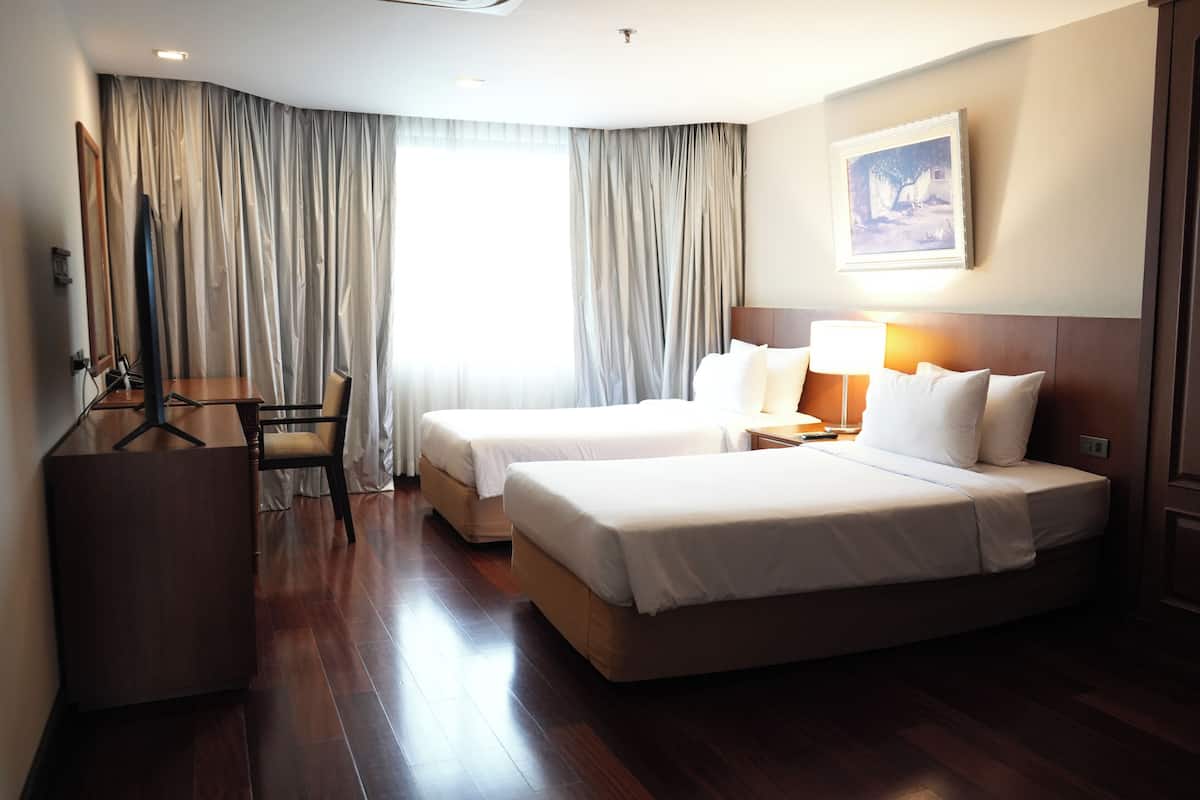 Une chambre d’hôtel avec deux lits, un bureau et une chaise.