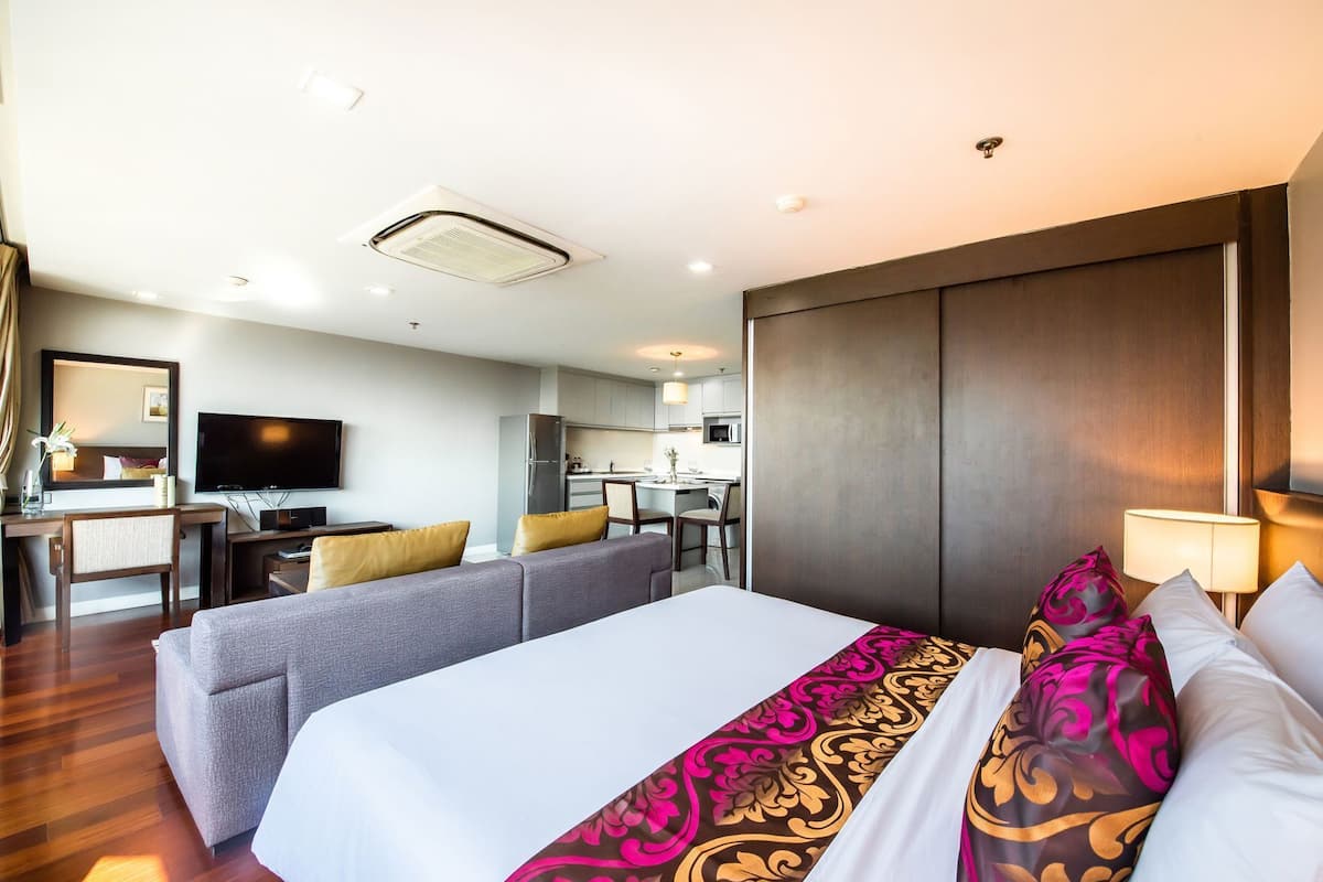 Une chambre d’hôtel comprenant un grand lit, un bureau avec une chaise, une télévision, une kitchenette et une salle de bain.
