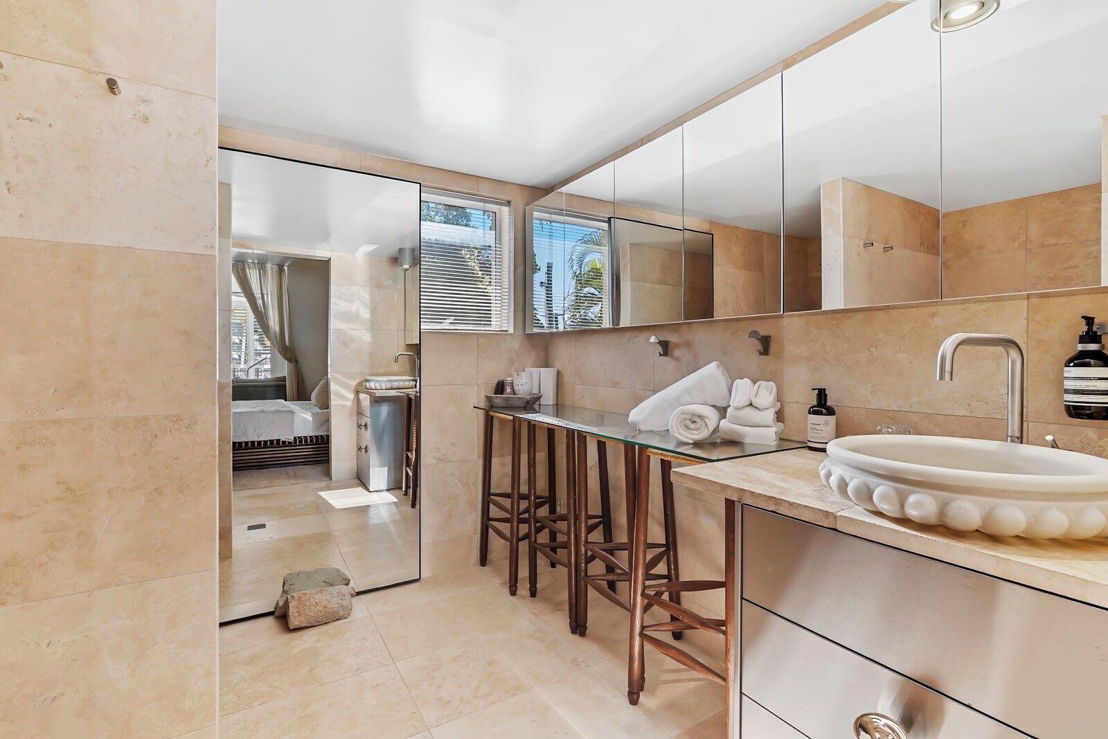 Une salle de bain moderne avec un grand lavabo, un miroir et des tabourets en bois.