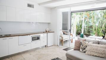 A modern kitchen with white cabinets and a large window overlooking a garden.