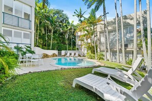 A pool area with lounge chairs, a dining table, and a small table with chairs. - Noosa Blue Resort (Noosa Heads)