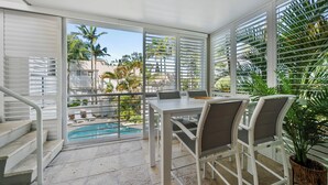 A balcony with a pool, white furniture, and a staircase.