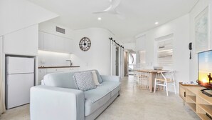 A modern kitchen with white cabinets, a built-in oven, and a ceiling fan.