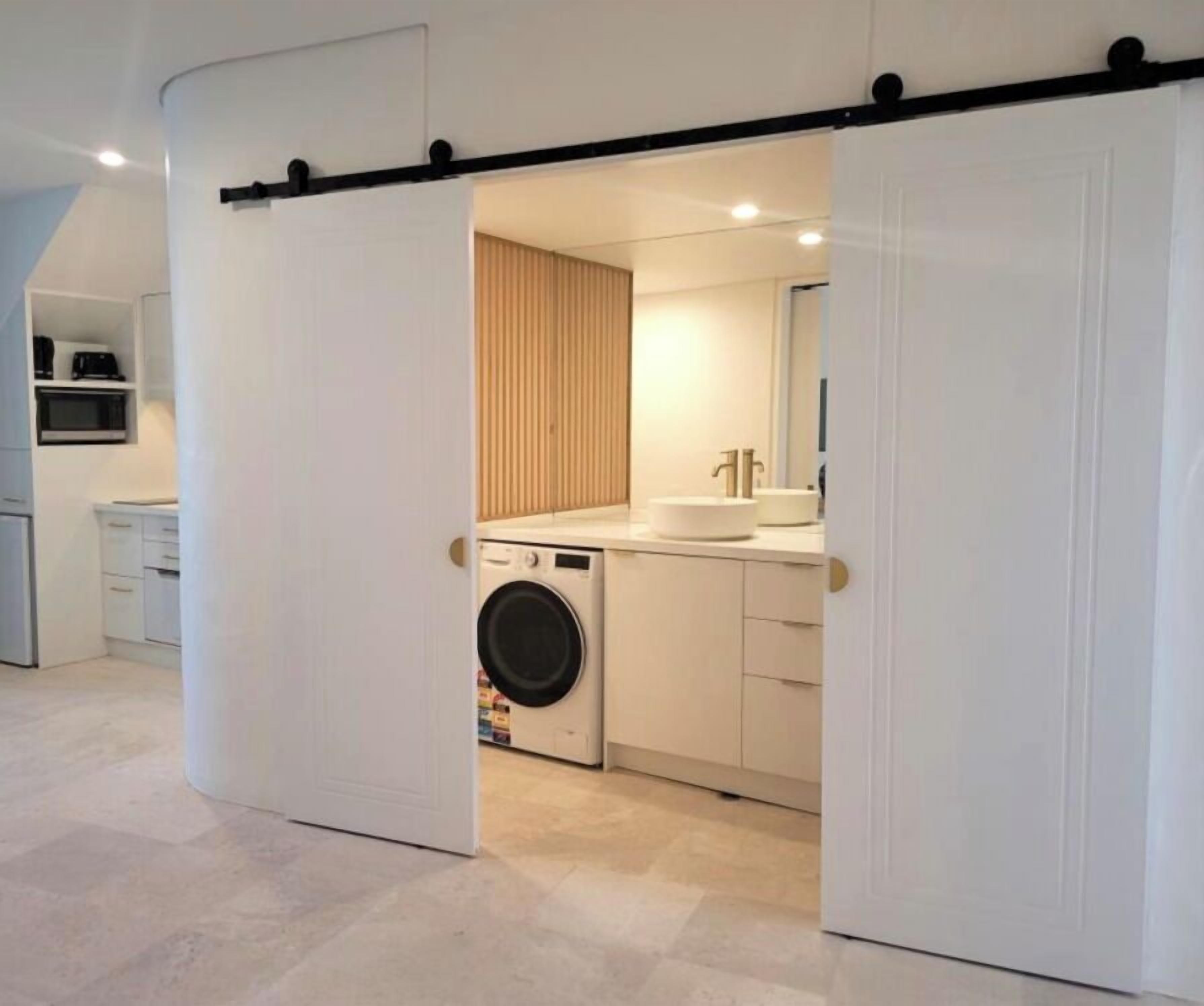 A modern kitchen with a washing machine, a sink, and a microwave.