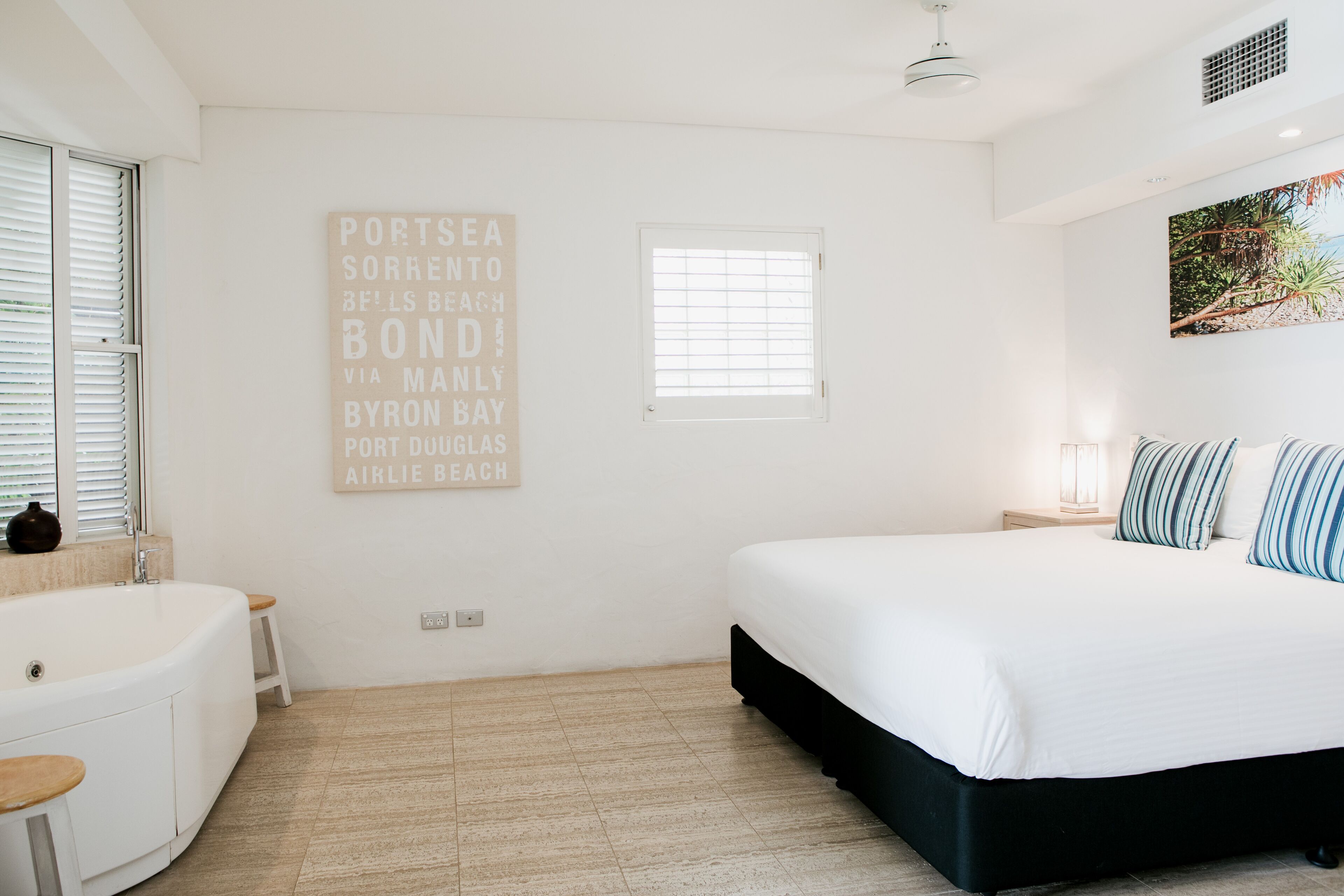 Un dormitorio con cama, ventana, un cartel en la pared y una bañera.