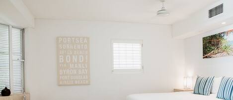 A bedroom with a bed, a window, a wall-mounted sign, and a bathtub.